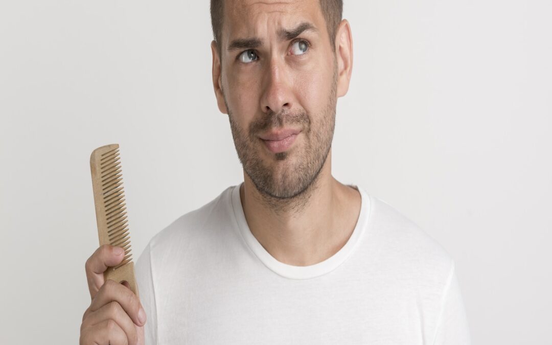 Hombre sosteniendo peine y preocupado por las hormonas y caída del pelo