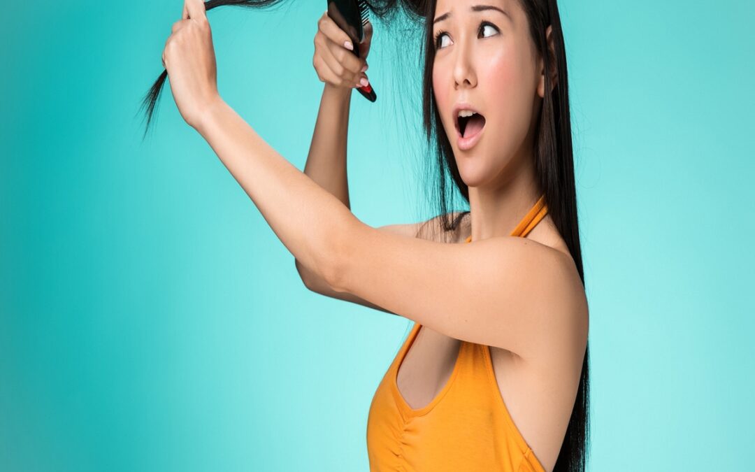 Mujer con remera amarilla peinándose y sufriendo uno de los tipos de alopecia en mujeres